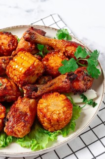Fried chicken drumsticks, Mexican style, with corn, on a plate, close-up