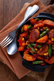 Steakhouse pfanne, fried potato slices, with meatballs, and vegetable mixture, on a black plate