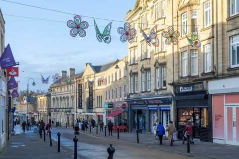 Christmas street decorations hang above quiet shopping street in January, town centre of