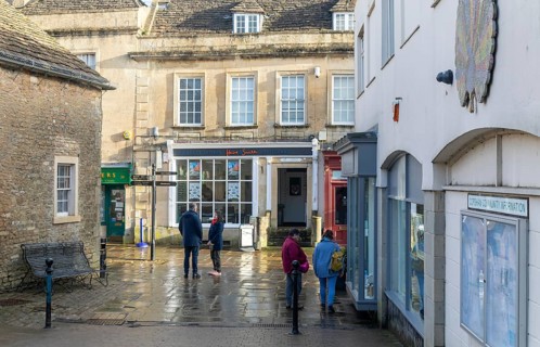 People in street wet surfaces after rain in town centre of Corsham Wiltshire, England, UK