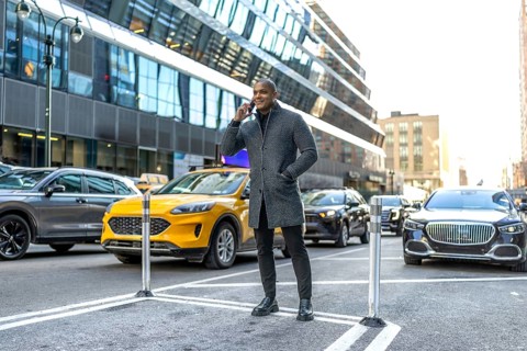 Man standing on a new york city street, making a phone call while surrounded by urban traffic and