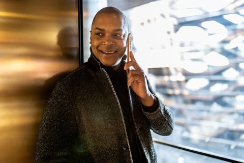 Smiling professional man engaging in a phone conversation, using a smartphone while standing