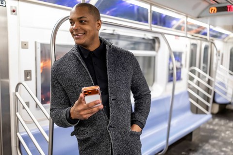 Young african american businessman standing on a subway train in new york city, smiling happily