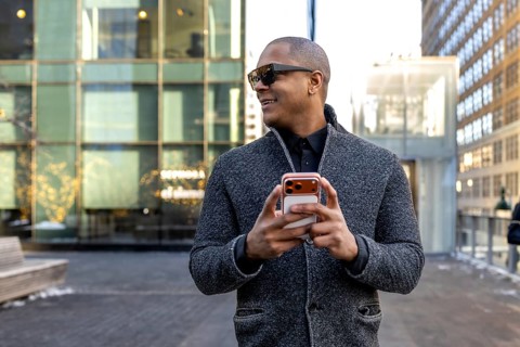 Professional black man smiling in a stylish gray jacket and sunglasses, walking manhattan streets