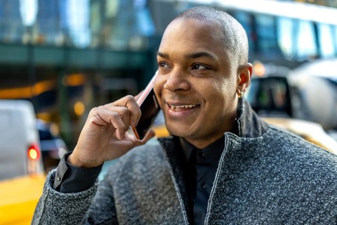 Smiling businessman in a suit hails manhattan streets while talking on his smartphone, engaged in a