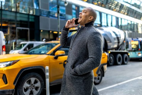 Young professional in a coat making a phone call while walking through a busy manhattan street with