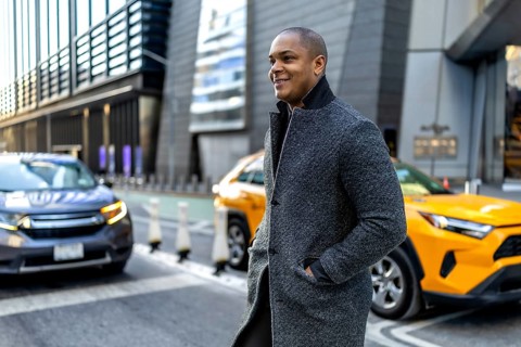 Happy young businessman walking through a busy downtown manhattan street, wearing a stylish gray