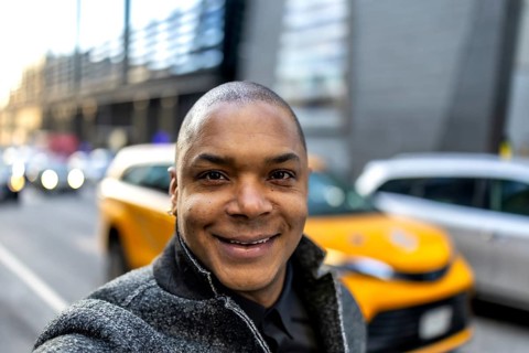 Smiling african american businessman taking a selfie on a vibrant city street, showcasing a