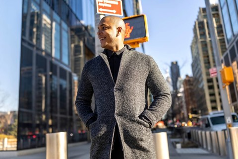 Young man smiling confidently as he walks through manhattan's financial district in smart casual