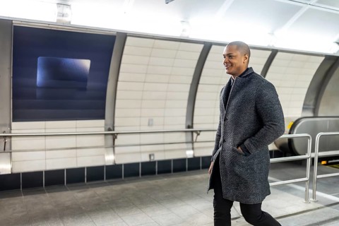 Businessman smiling and walking purposefully through a modern subway station, feeling confident and