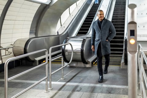 Professional man commuting through a modern subway station, coming down an escalator with a