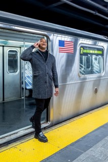Happy professional man smiling and talking on smartphone while stepping onto a manhattan subway