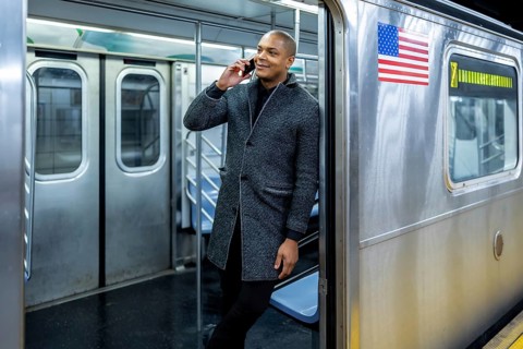 Smiling businessman traveling on a new york city subway train, talking on a mobile phone,