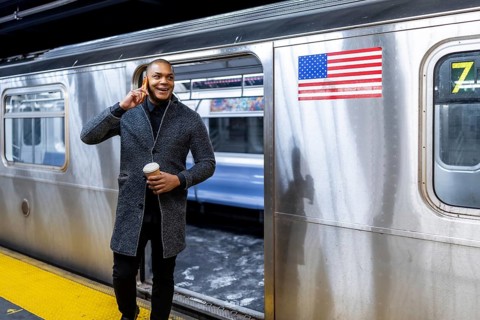 Young businessman commuting in new york city, holding a cup of coffee and having a conversation on