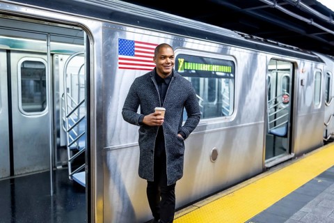 African american professional standing on a manhattan subway platform holding a coffee cup and
