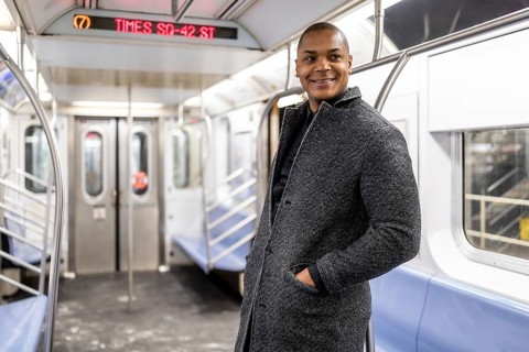 Happy black businessman standing inside an nearly empty new york subway car, smiling as he commutes