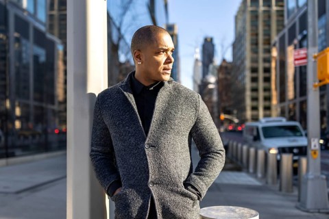 Professional man thinking while standing on a busy new york city street, wearing a stylish gray