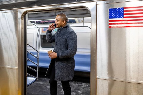 Man holding a coffee cup and having a conversation on his mobile phone, standing inside a new york