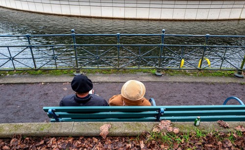 Senior couple sitting on a park bench at the Tegel harbor basin, Berlin, Germany