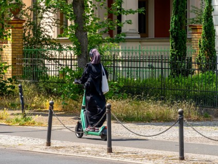 Woman wearing headphones riding on an electric scooter, Potsdam, Brandenburg, Germany