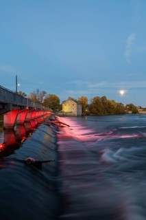 Illuminated Moulin Neuf water flow control dam and walkway over Des Mille-Iles river plus New Mill