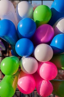Close-up of colourful balloons inflated with helium gas and attached to black metal lattice support