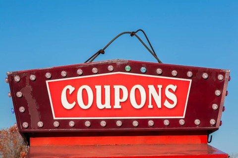 Close-up of the word coupons spelled out in bold white letters on red and maroon colored banner,