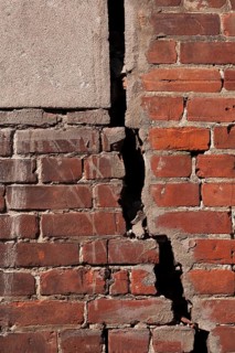 Close-up of large and deep wide open crack on exterior wall of red brick building, Quebec, Canada
