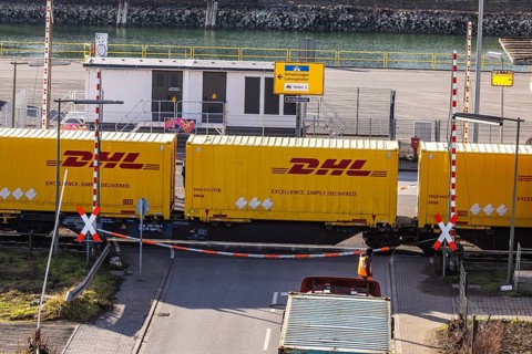 Freight train loaded with yellow container from DHL. Railway crossing in the port area of Mannheim,
