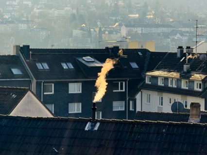 Smoke plume from a chimney over densely built residential area in the evening light, wintry city