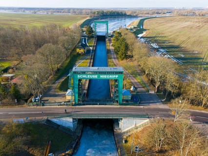 Close-up of Niegripp lock seen over a flat bridge with surrounding forest, aerial view, Niegripp