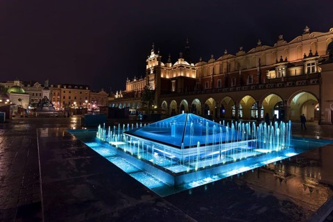 Illuminated fountain with cloth halls at night, Market Square, Krakow, Poland