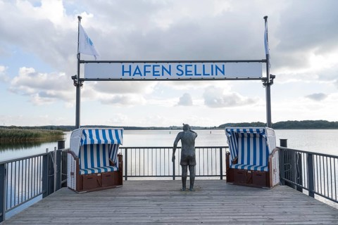 Viewing platform with two beach chairs and a sculpture that looks like a person, sign with flag,