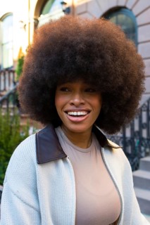 African american woman with natural curly afro hairstyle smiling outdoors, representing beauty,
