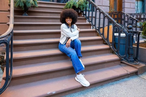 Young african american woman with afro hair sitting on a brownstone stoop in a new york city
