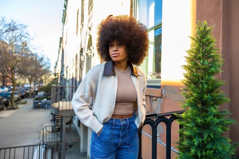 Young woman with an impressive afro hairstyle and casual fashion standing on a residential street