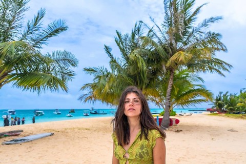 Woman standing on a tropical beach in the maldives, surrounded by sand, palm trees, and turquoise