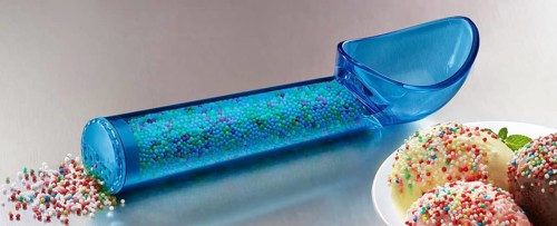 Blue, transparent ice cream scoop filled with coloured sugar sprinkles, next to a plate with