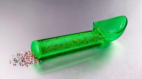 Green, transparent ice cream scoop filled with colored sugar sprinkles