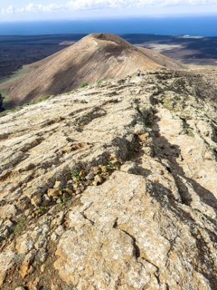 View from Caldera Blanca volcano against blue sky with white clouds, Mancha Blanca, Lanzarote,