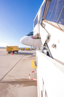 Close-up of an airplane staircase at an airport with Eurowings aircraft in the background,