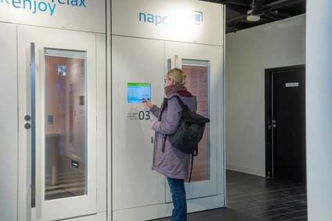 Woman operating screen on modern indoor sleeping cabin, Stuttgart Airport, Germany