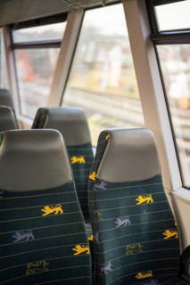 Two train seats with blue fabric and yellow lion patterns next to train windows in the interior,