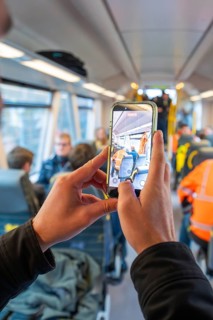 Man taking a photo with a smartphone in a busy train interior, taking the Hermann Hessebahn, Calw,