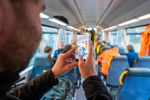 Person photographs the interior of a train and other passengers with a smartphone, Hermann