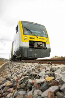 SWEG train on rails with pebbles in the foreground under cloudy sky, taking off the Hermann