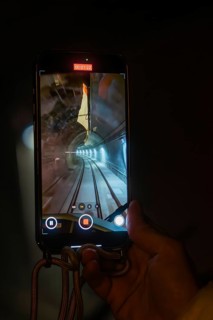 A smartphone shows the inside view of a tunnel crossed by a train, held by one hand, the Hermann