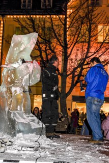 Ice carving artist in front of his ice sculpture interviewed by a GEA reporter during ice carving