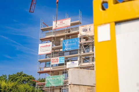 Multi-storey scaffolding structure with company logos on a sunny construction site, carpentry, new