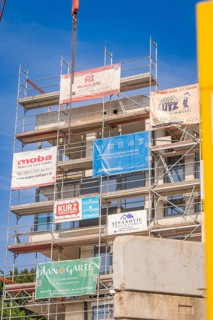 Multi-storey scaffolding on a building with various company banners, carpentry, new building,